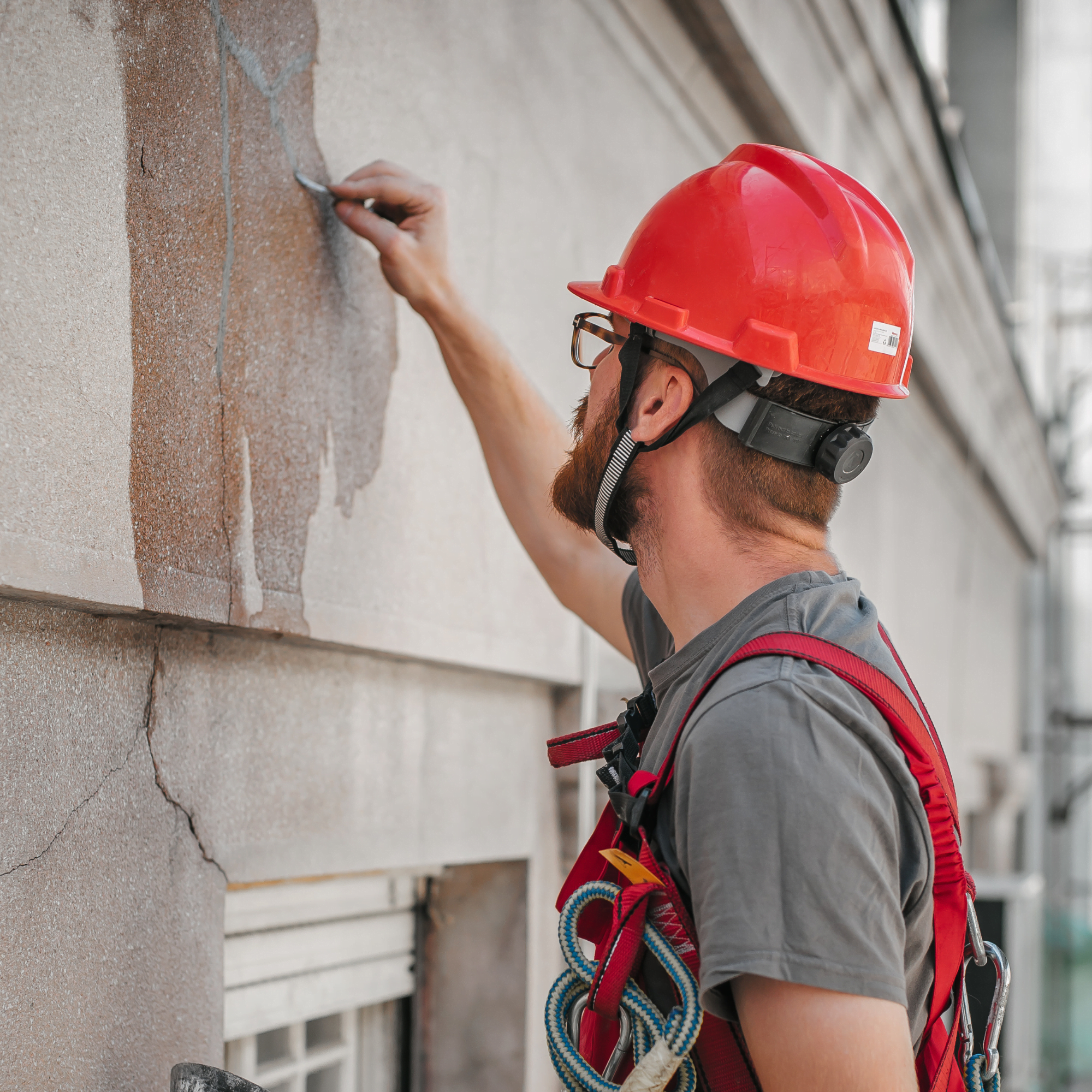 Un ouvrier debout sur un échafaudage effectue des travaux de restauration de la façade d'un vieux bâtiment. Réparer et rénover