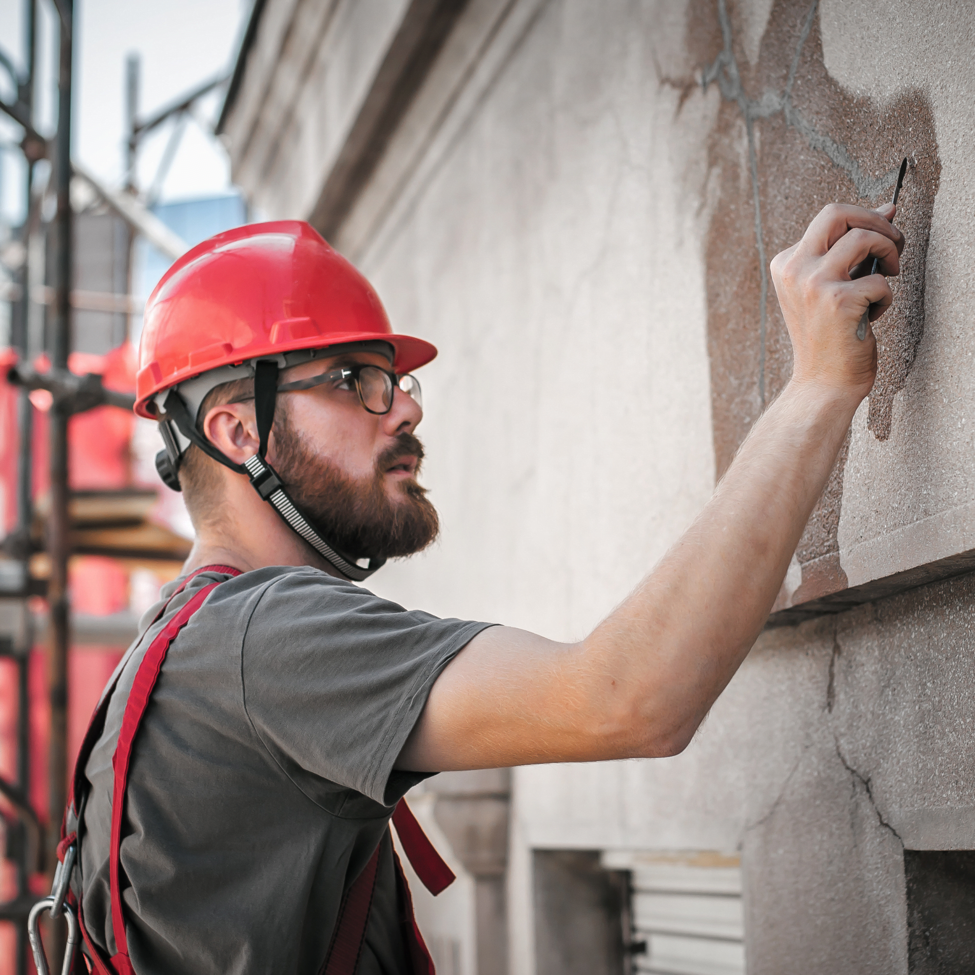 Un ouvrier debout sur un échafaudage effectue des travaux de restauration de la façade d'un vieux bâtiment. Réparer et rénover